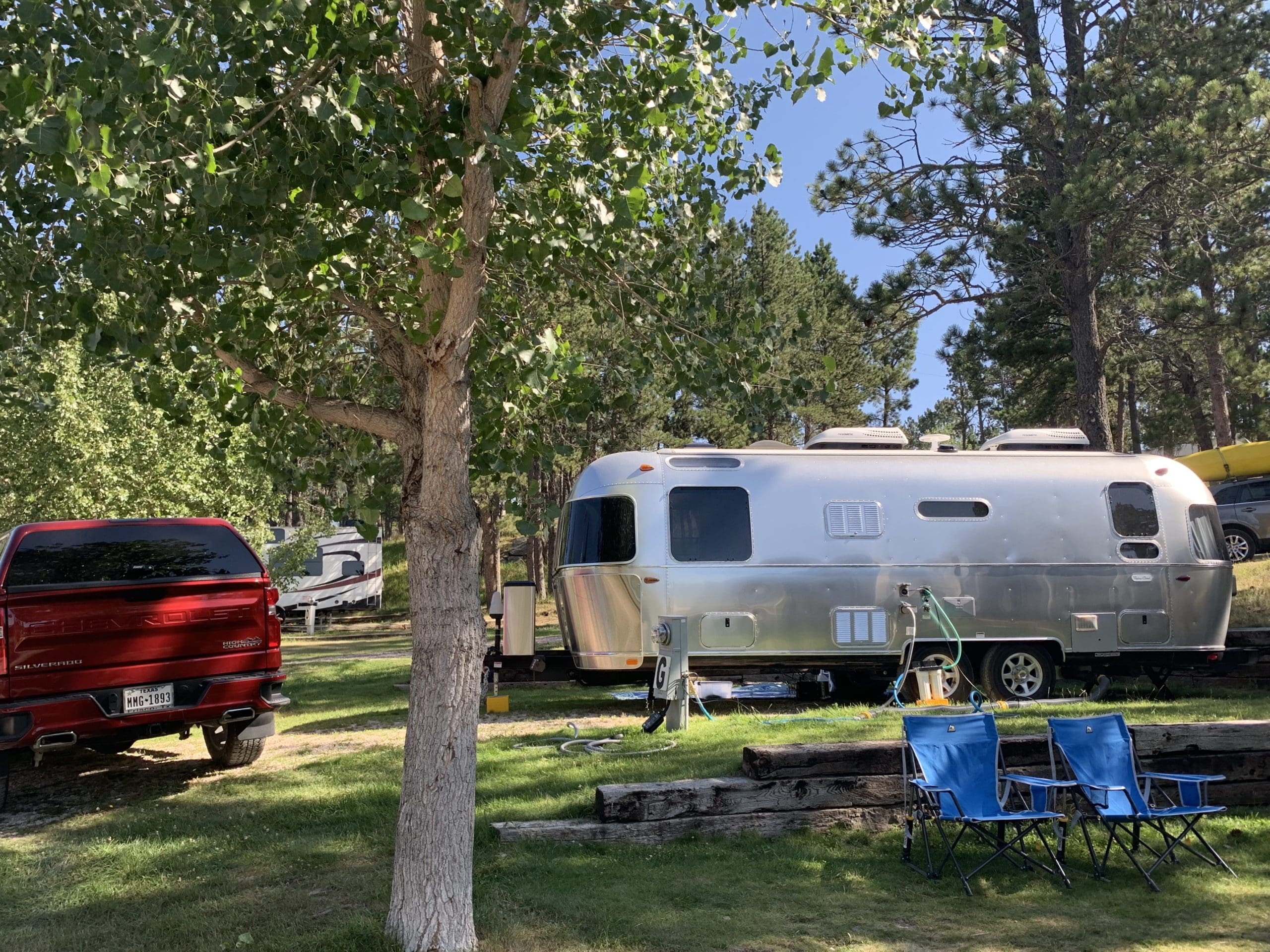 smooth silver airstream camper trailer parked at a RV spot at Beaver Lake Campground with a red truck