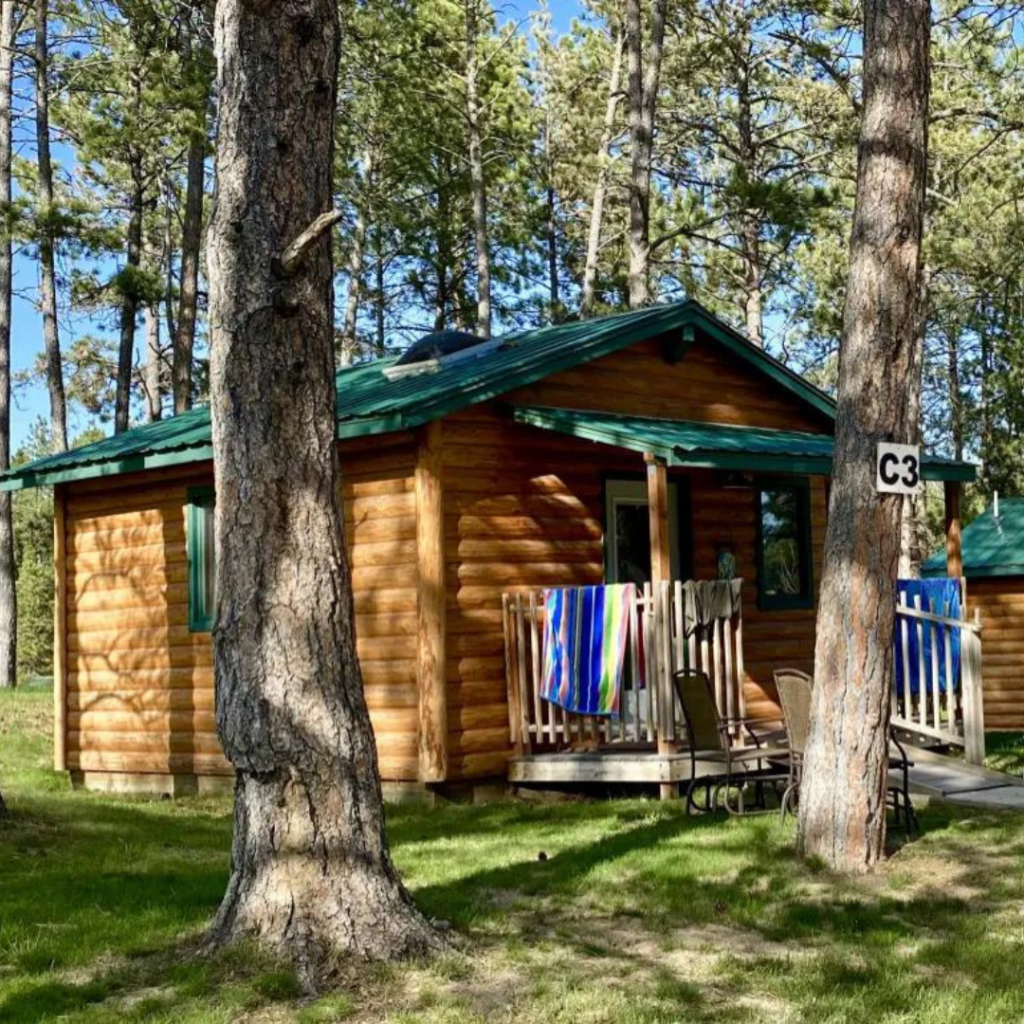 Campground Cabin with porch in the pine trees at Beaver Lake Campground in Custer, SD