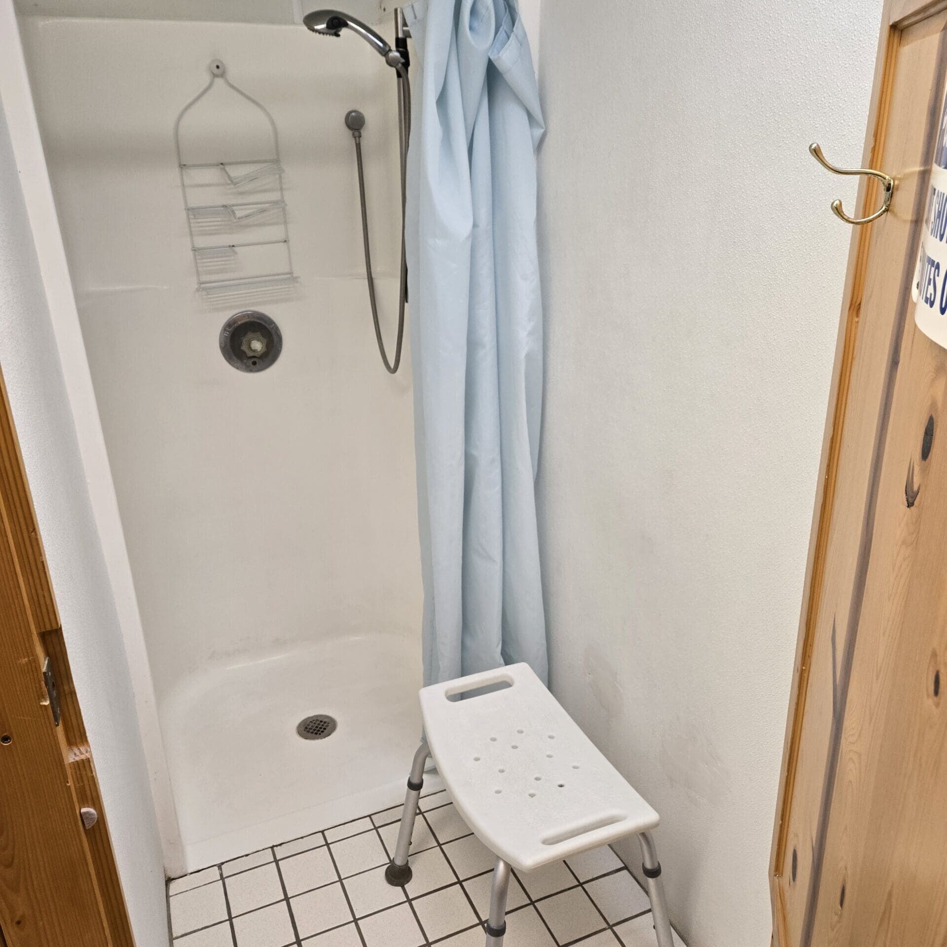 Interior view of shower area in the bathhouse at Beaver Lake Campground with seating area, shower and hangers